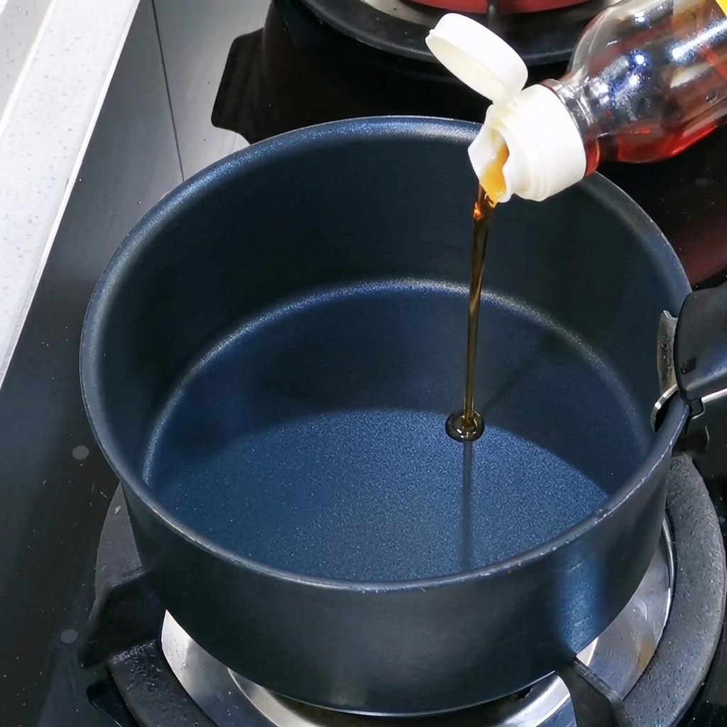 Huile de sésame versée dans une marmite noire sur le feu.