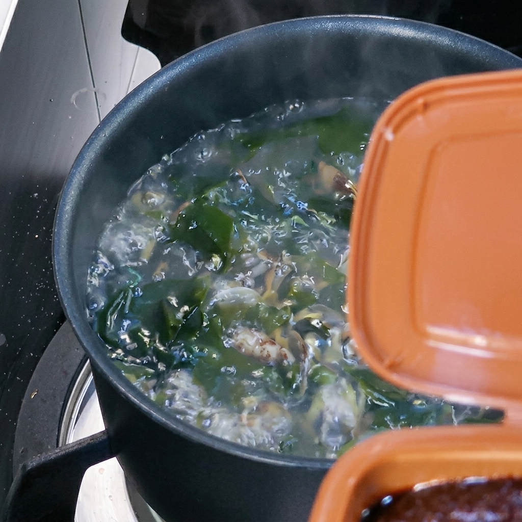 Une cuillerée de pâte de soja brune incorporée à la soupe bouillante.