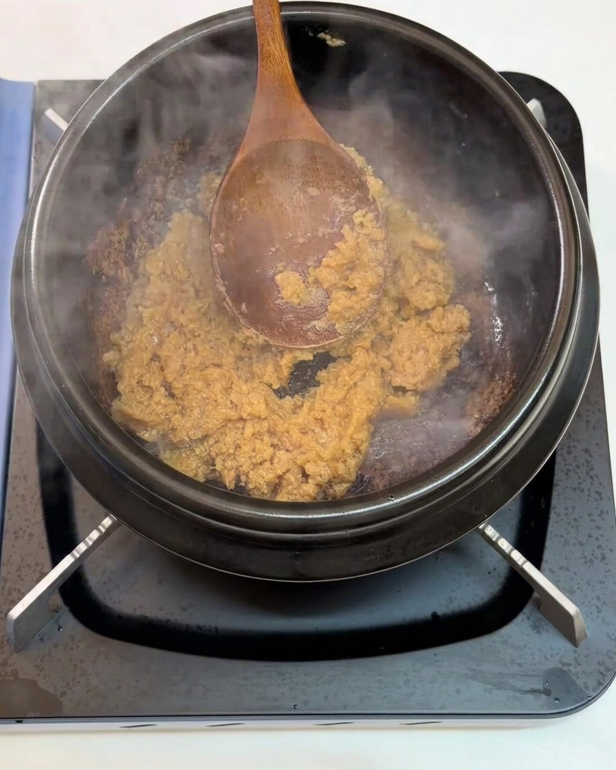 Ail émincé incorporé à la pâte de soja en train de revenir dans le pot.