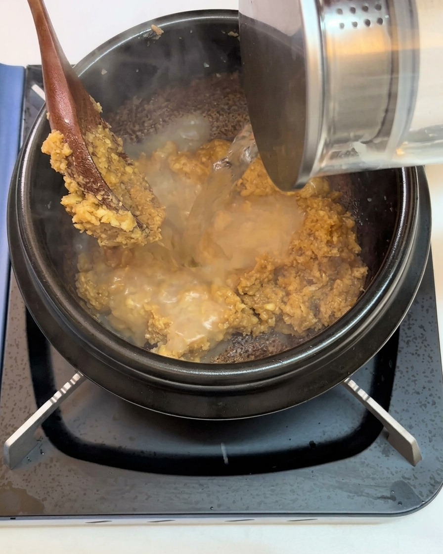 De leau versée dans le pot sur le mélange de pâte de soja et dail.