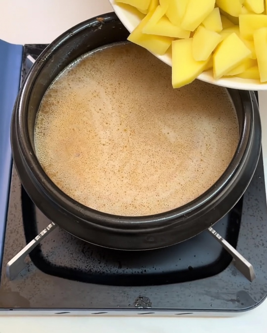 Pommes de terre et autres ingrédients hachés ajoutés dans le bouillon bouillant.