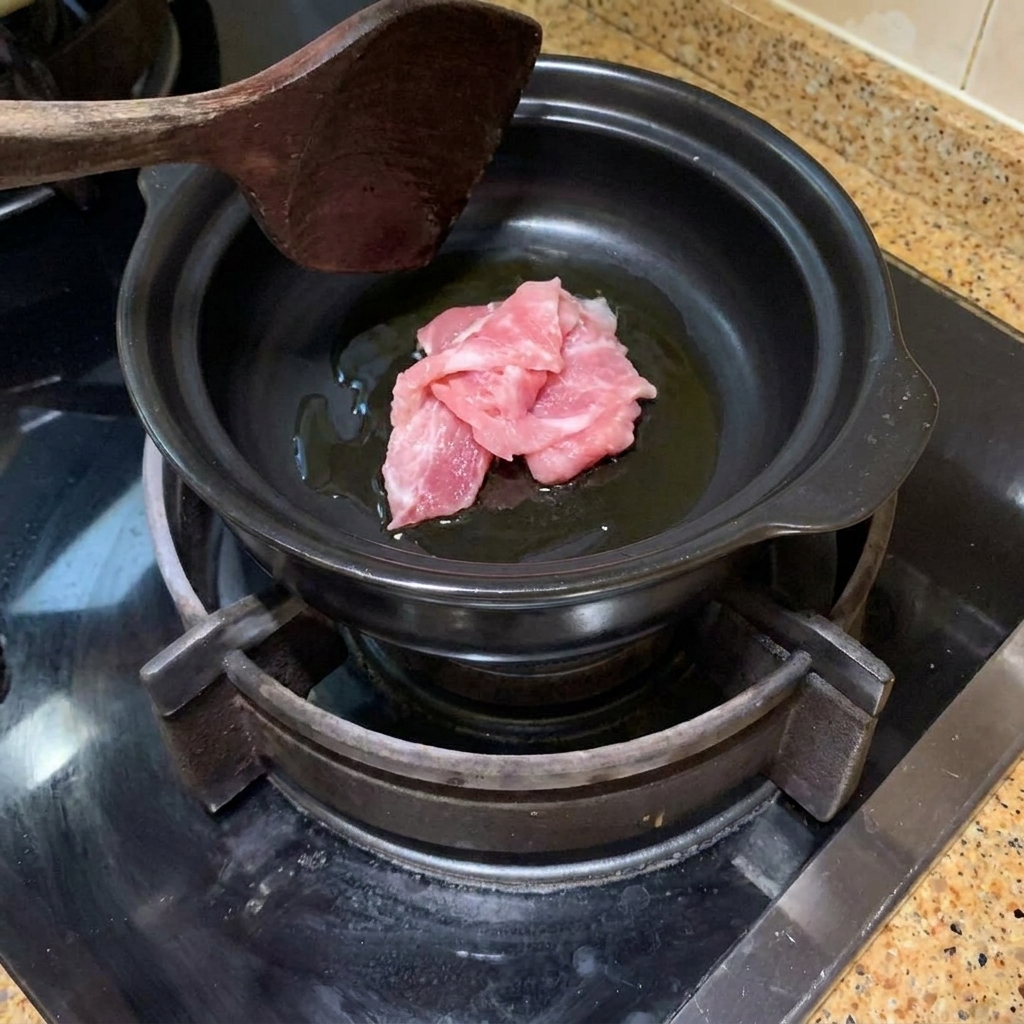 Tranches de porc sautées dans une marmite en terre cuite chaude avec de lhuile.