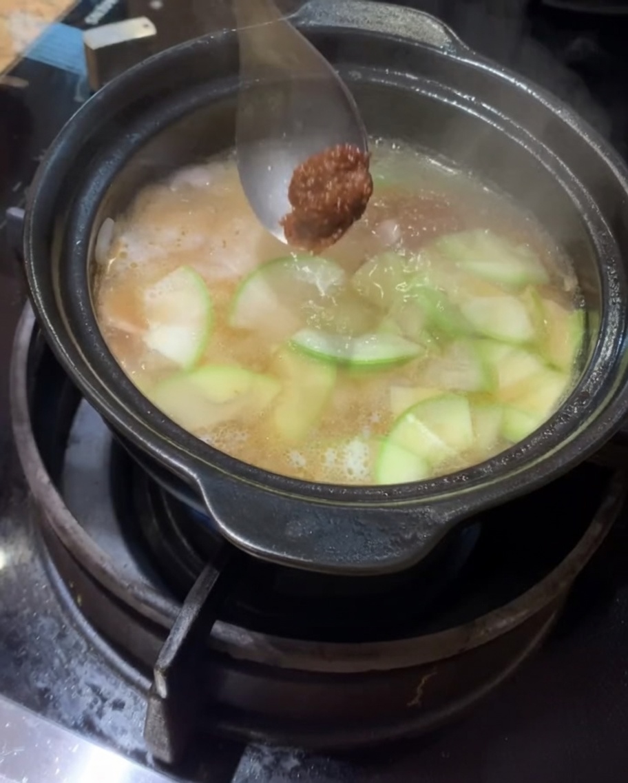 Pâte de soja et pâte de piment ajoutées dans la marmite frémissante.