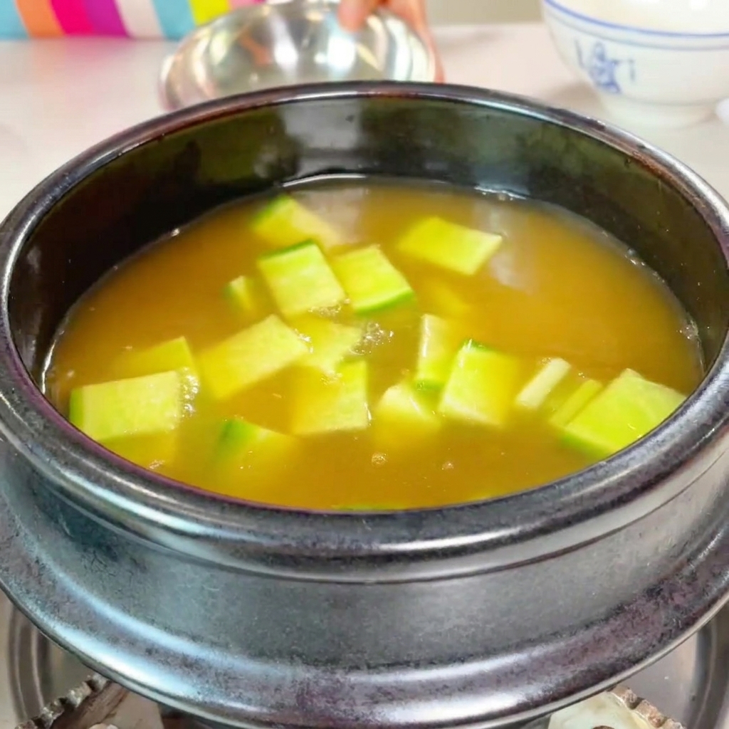 Courgette verte en dés et champignons tranchés ajoutés dans la marmite.