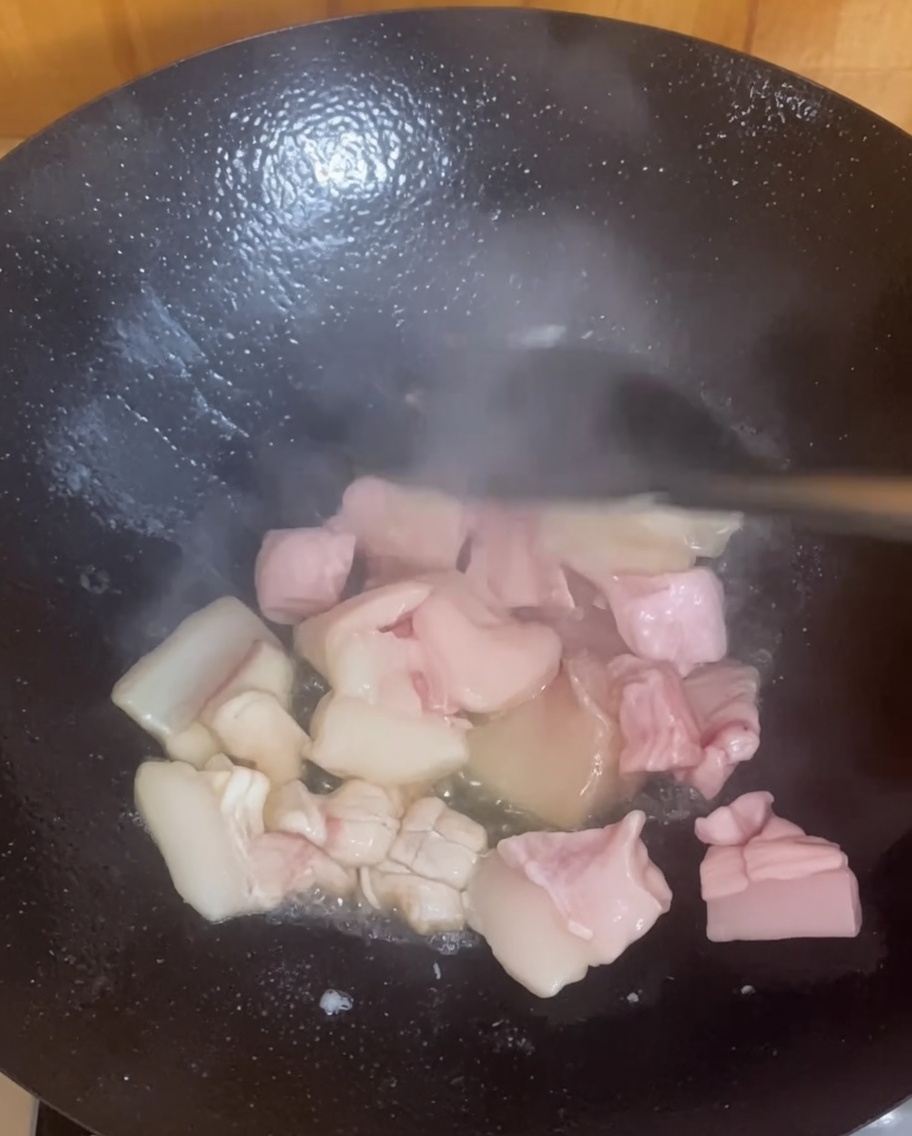 Morceaux de poitrine de porc grésillant et dorant dans un wok chaud.