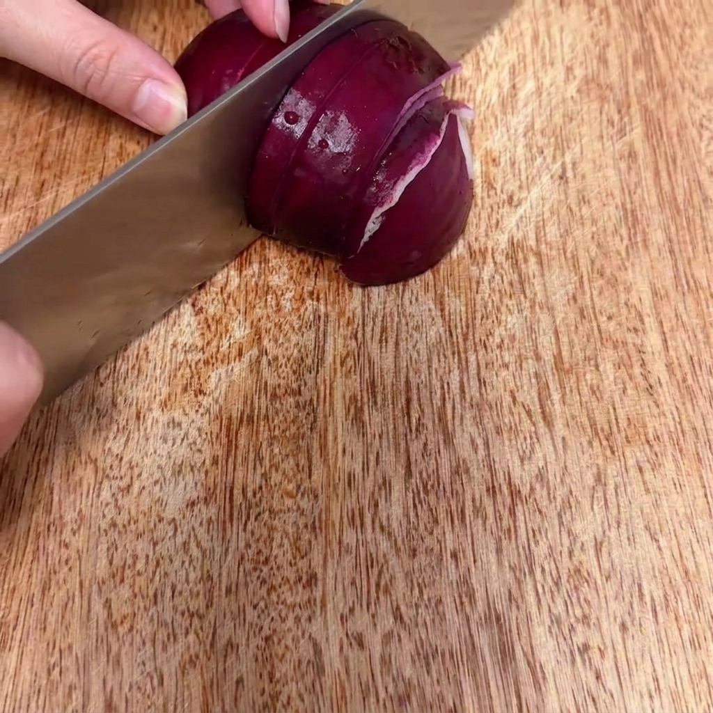 Oignon rouge en cours de hachage en petits morceaux fins sur une surface en bois.