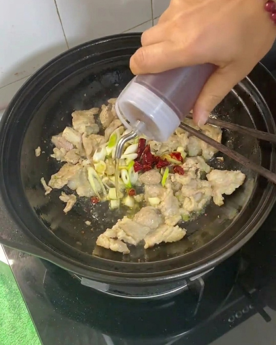 Vin de cuisine versé dans la cocotte contenant le porc et les aromates.