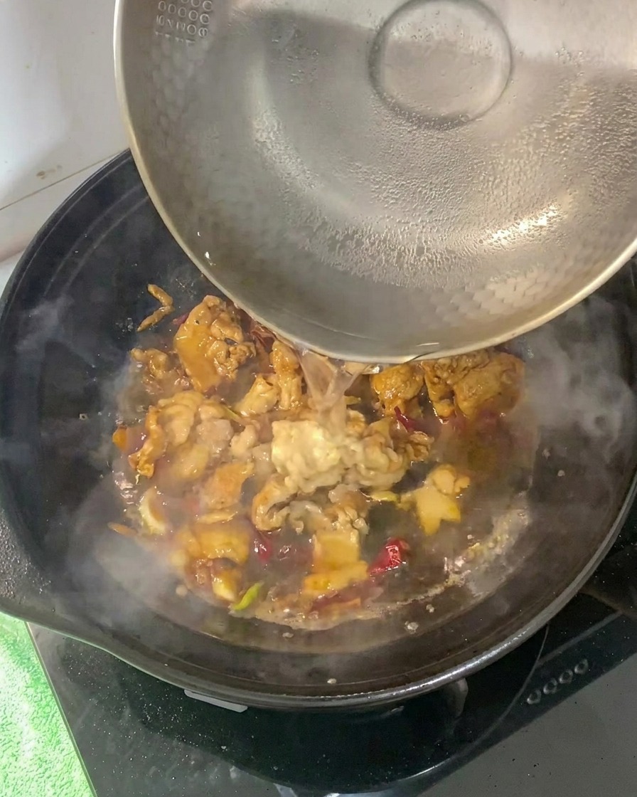 Eau chaude versée dans la cocotte avec la base de porc assaisonnée.