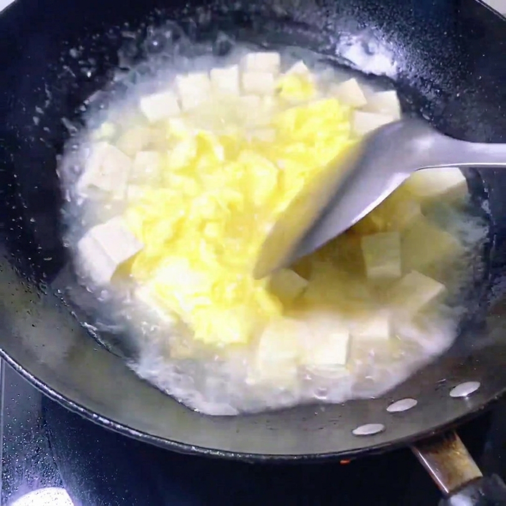 Palourdes fraîches placées dans une poêle contenant un mélange de bouillon et de tofu.