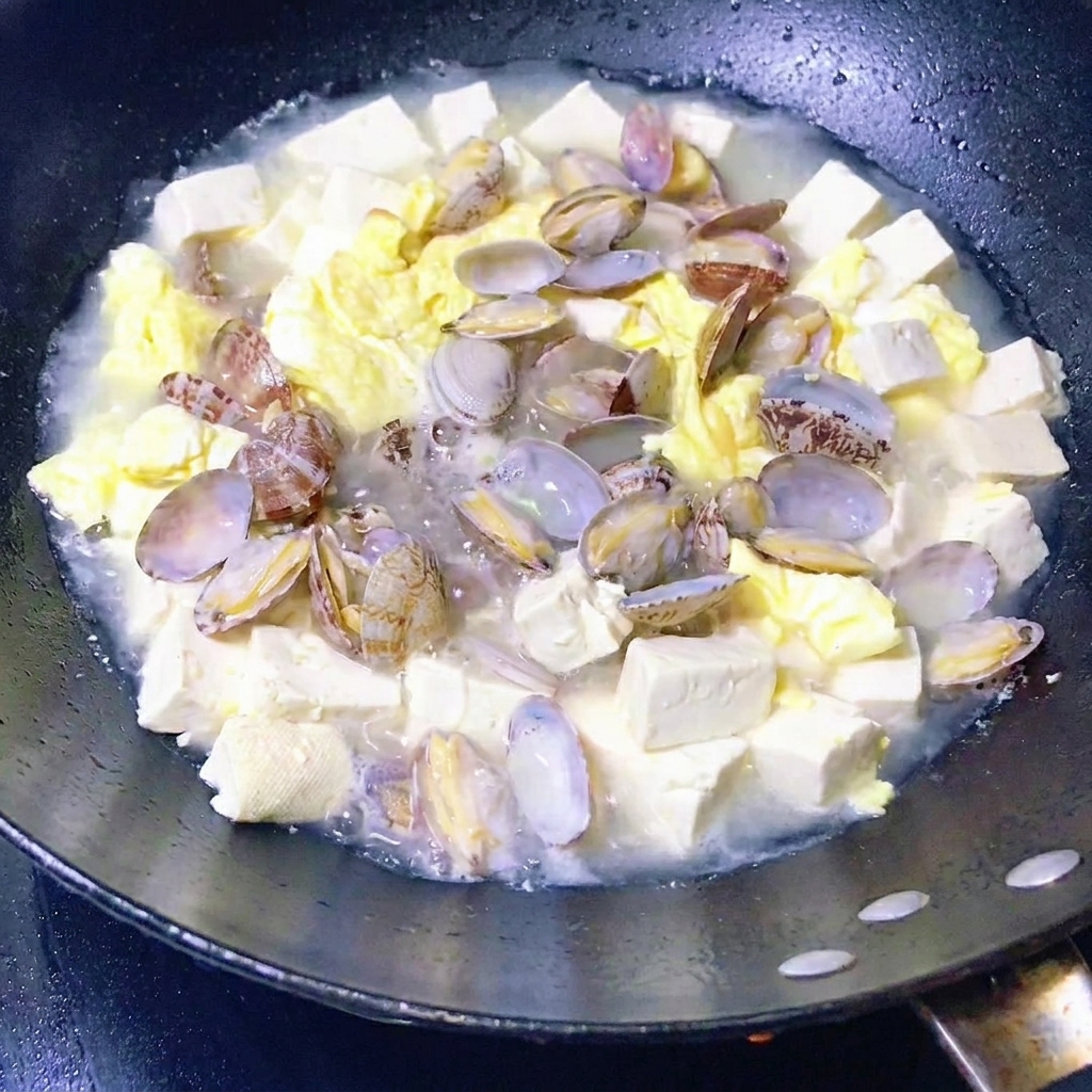 Légumes verts à feuilles ajoutés dans la poêle de ragoût de palourdes et tofu.
