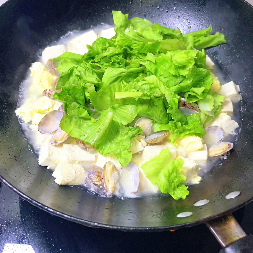 Un ragoût de palourdes et tofu fini, mélangé doucement avec une louche.