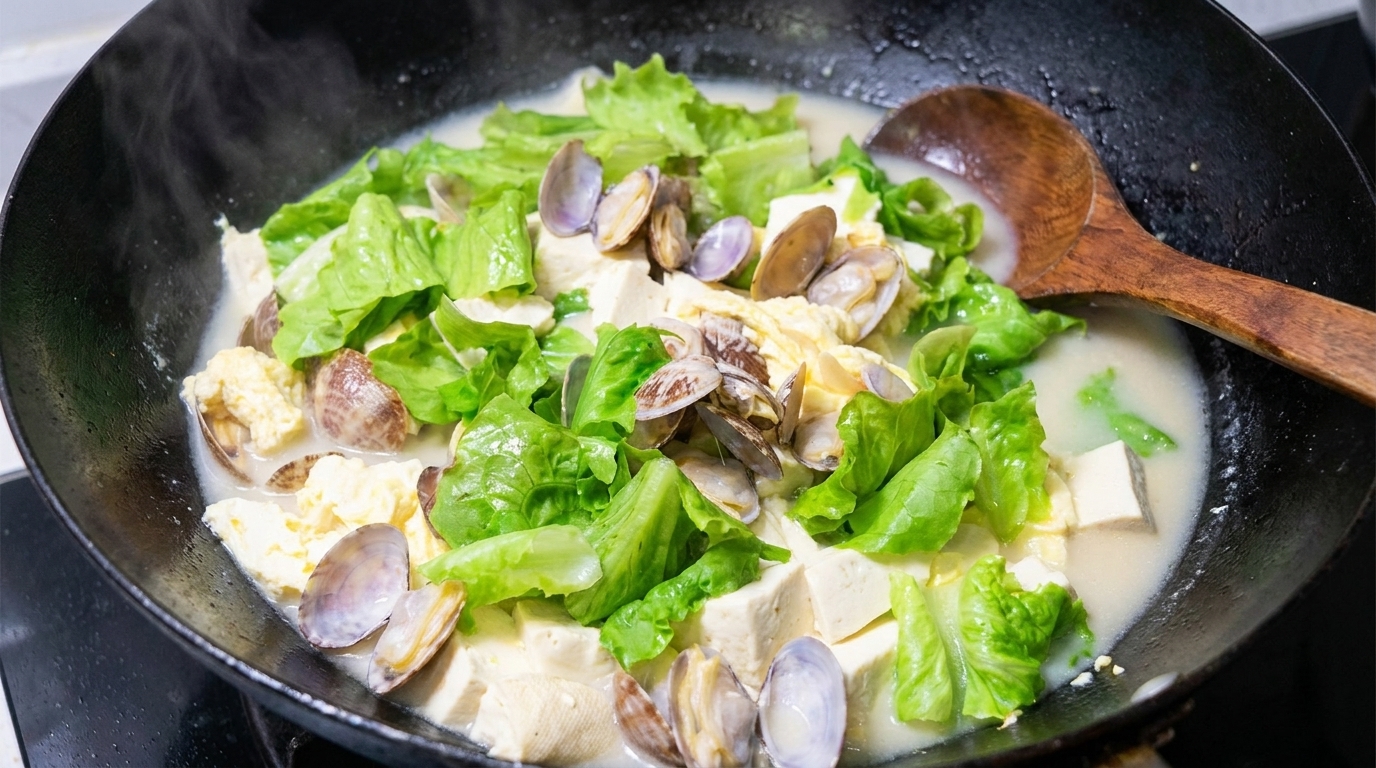 Une poêlée généreuse de ragoût de palourdes et tofu, avec un bouillon crémeux aux œufs, du tofu soyeux et des palourdes fraîches.