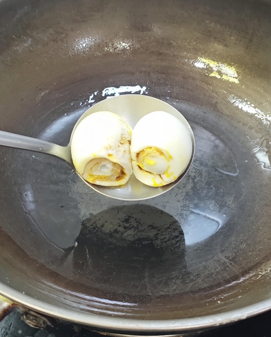 Deux œufs de cane salés grésillant dans un wok chaud avec de lhuile.
