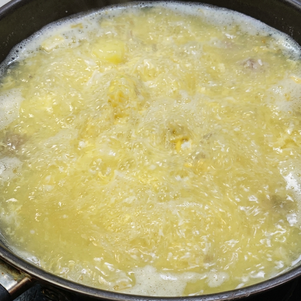 Sel et poivre blanc ajoutés à la soupe de tofu et œufs salés frémissante.