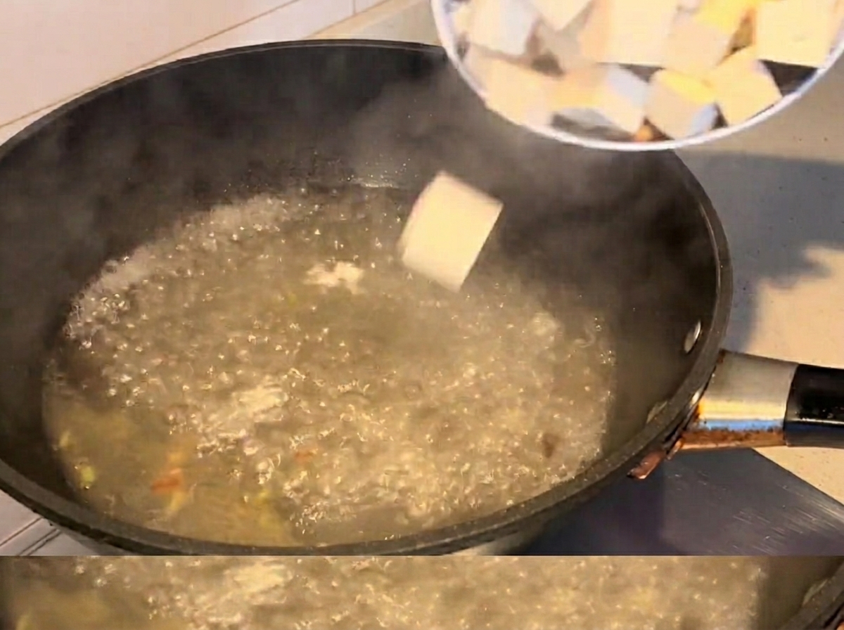 Cubes de tofu et palourdes cuisant dans la soupe bouillante.
