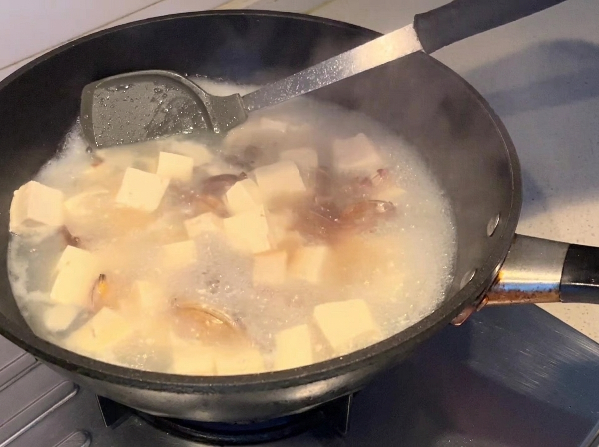 Sauce soja versée dans la soupe frémissante.