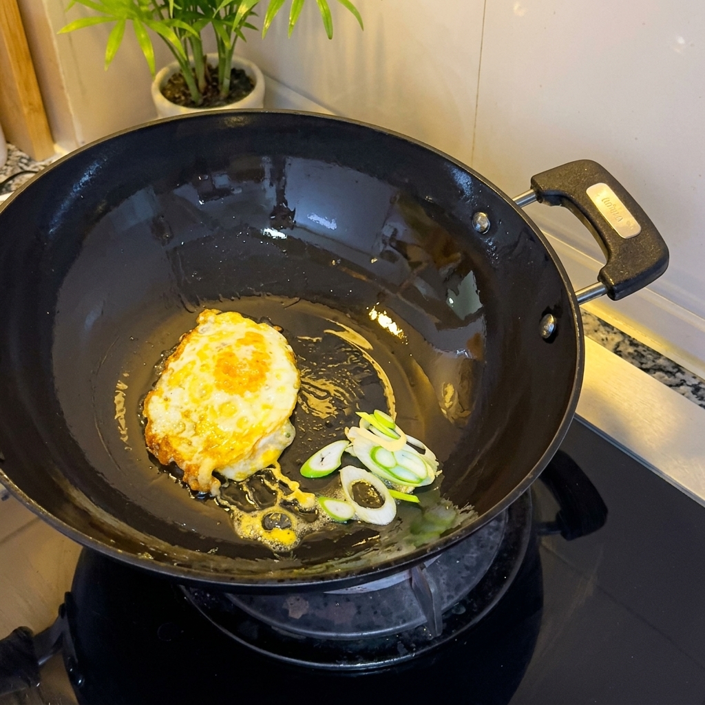 Lœuf frit et les oignons verts hachés grésillant dans le wok.