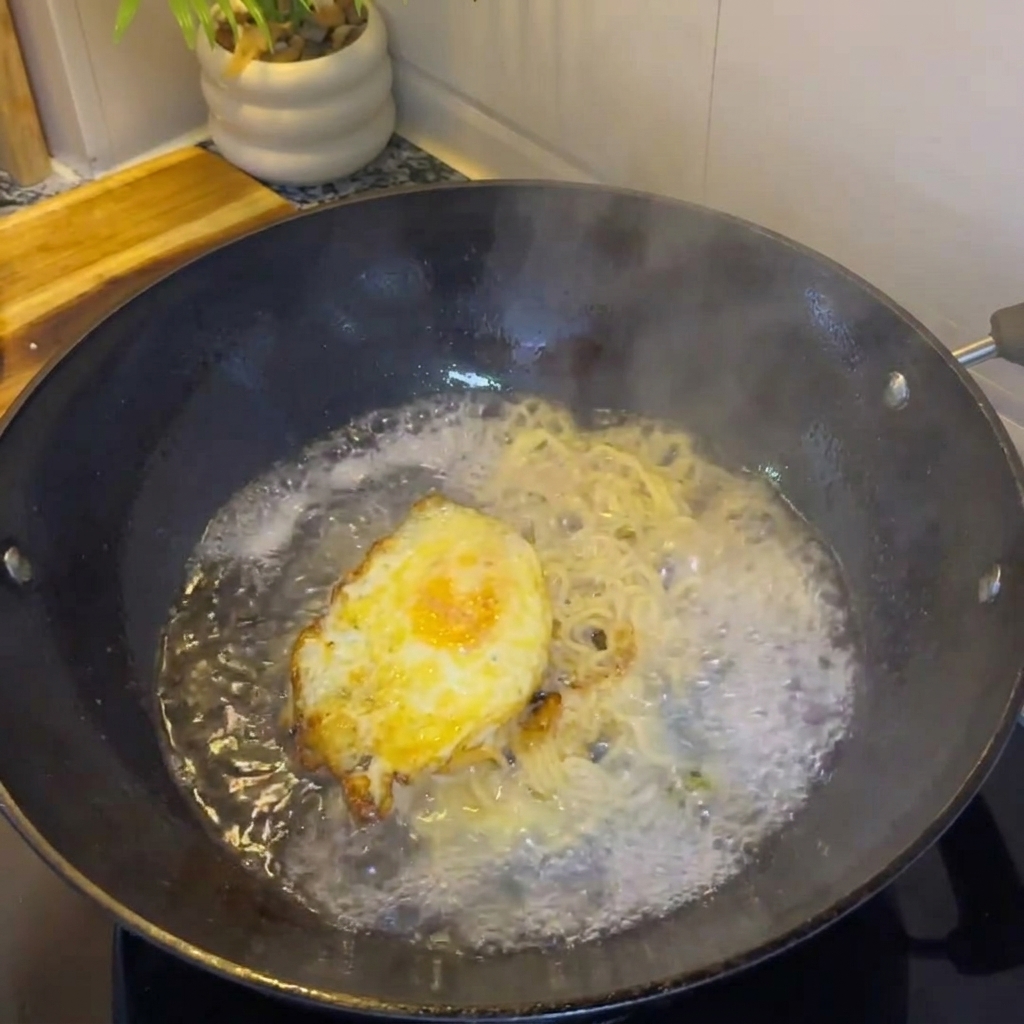 De leau chaude versée dans le wok avec lœuf et les oignons, créant un bouillon.
