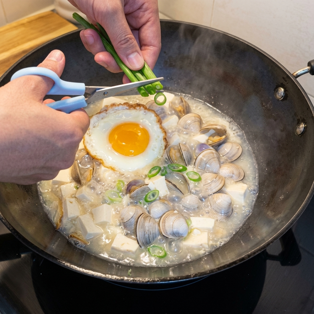 Oignons verts fraîchement hachés saupoudrés dans une marmite bouillonnante de soupe au tofu et palourdes.