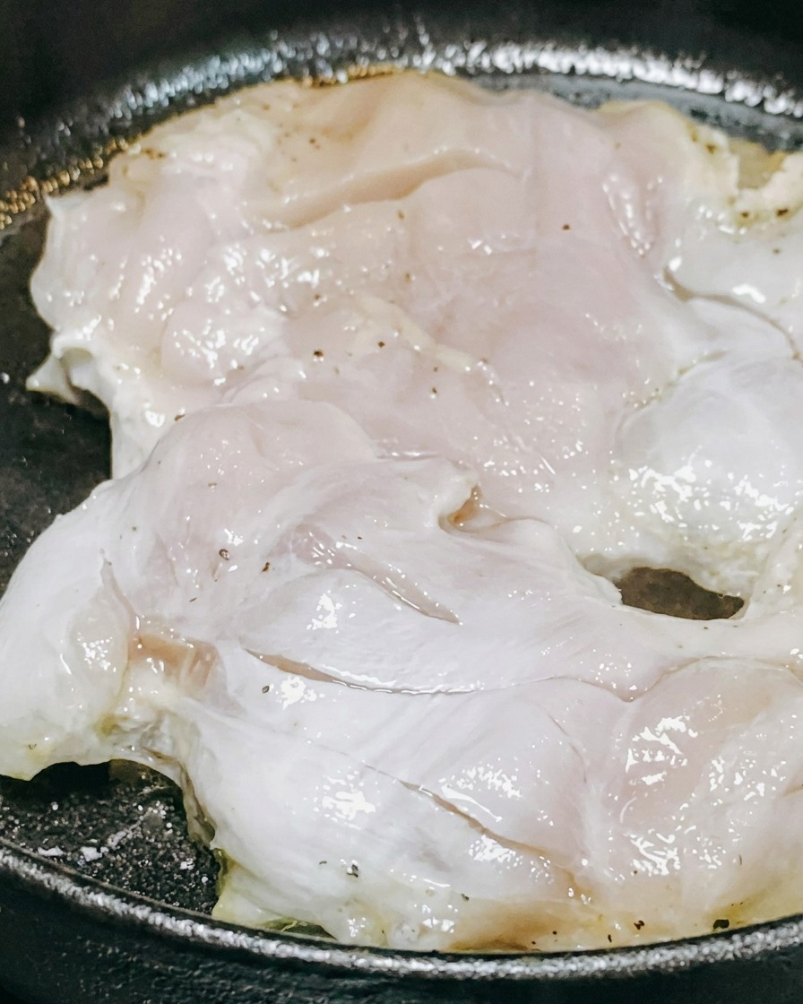 Sauce teriyaki et vin blanc versés sur les morceaux de poulet en cours de cuisson.