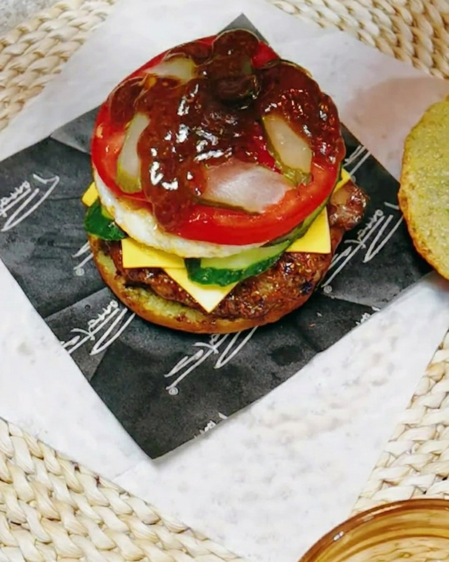 Gros plan sur le burger arrosé dune sauce teriyaki sombre mélangée à du jus de citron.