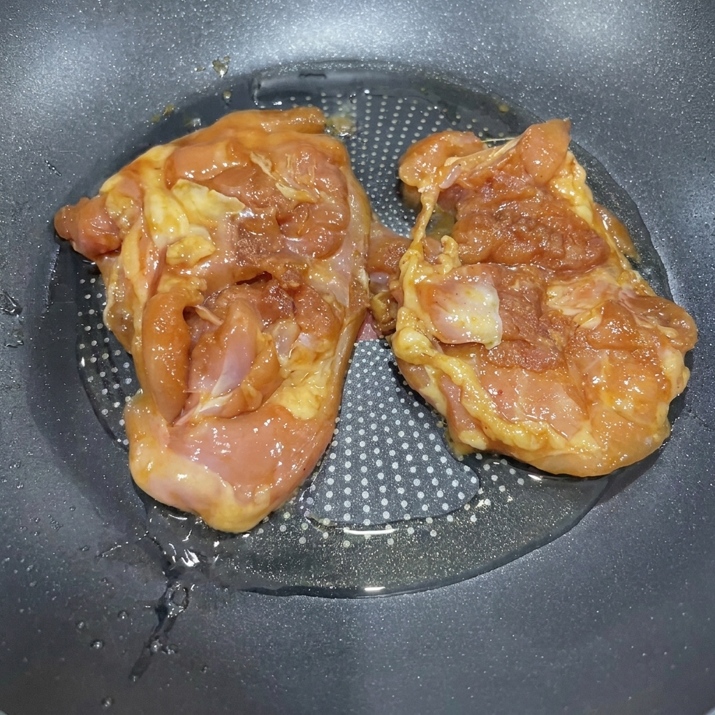 Hauts de cuisse de poulet marinés grésillant dans une poêle avec de lhuile chaude.