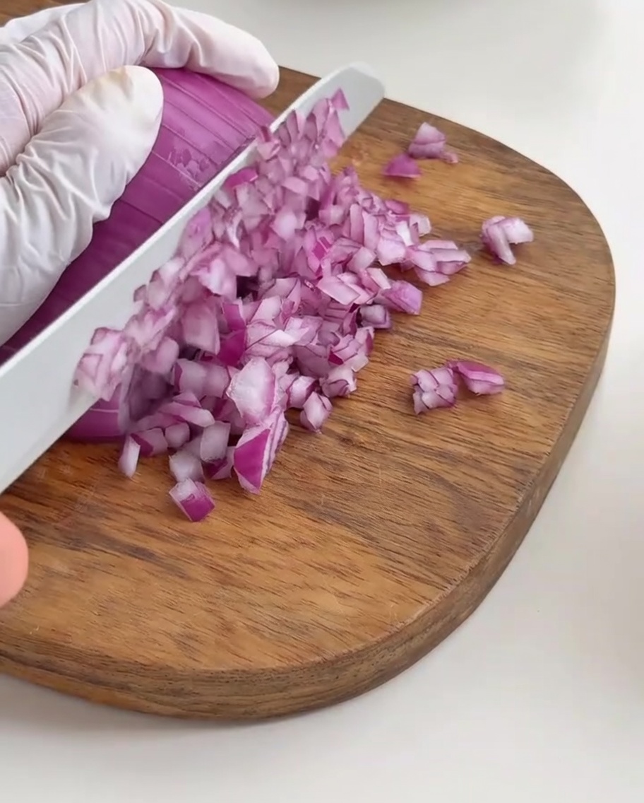 Oignon rouge finement ciselé sur une planche.