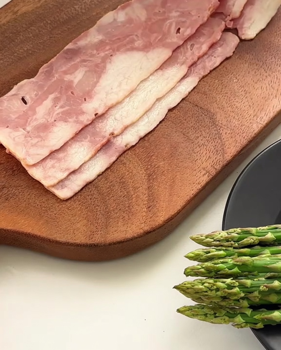 Gros plan dun couteau coupant des tranches de bacon en petits morceaux sur une planche en bois.