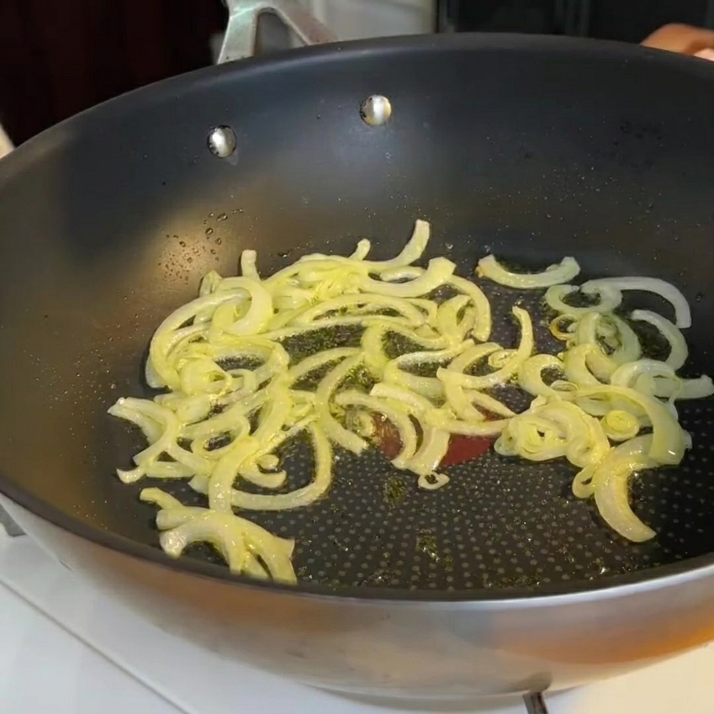 Morceaux dasperges ajoutés dans une poêle contenant les oignons sautés.