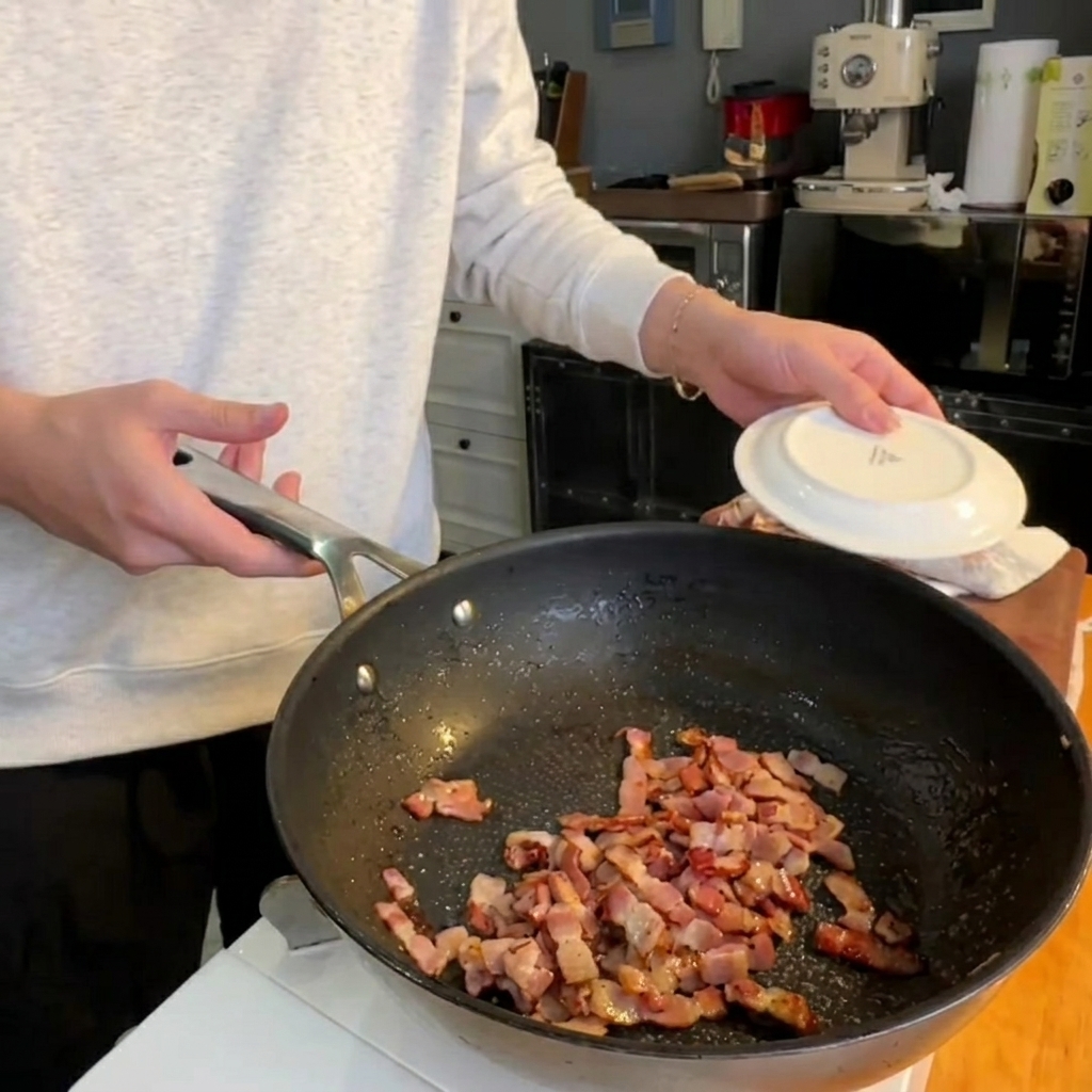 Pointes dasperges frites dans une poêle avec les morceaux de pancetta croustillants.