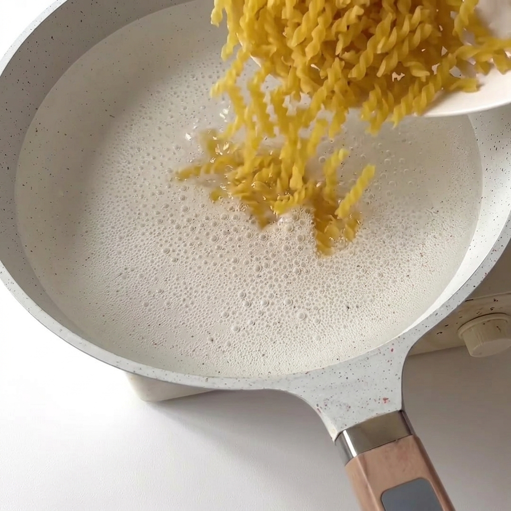 Fusilli tombant dans une casserole deau bouillante frémissante.