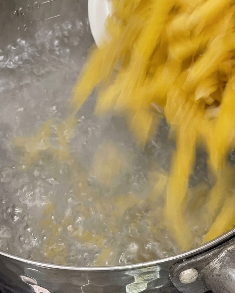 Pâtes crues versées dans une casserole deau bouillante frémissante.