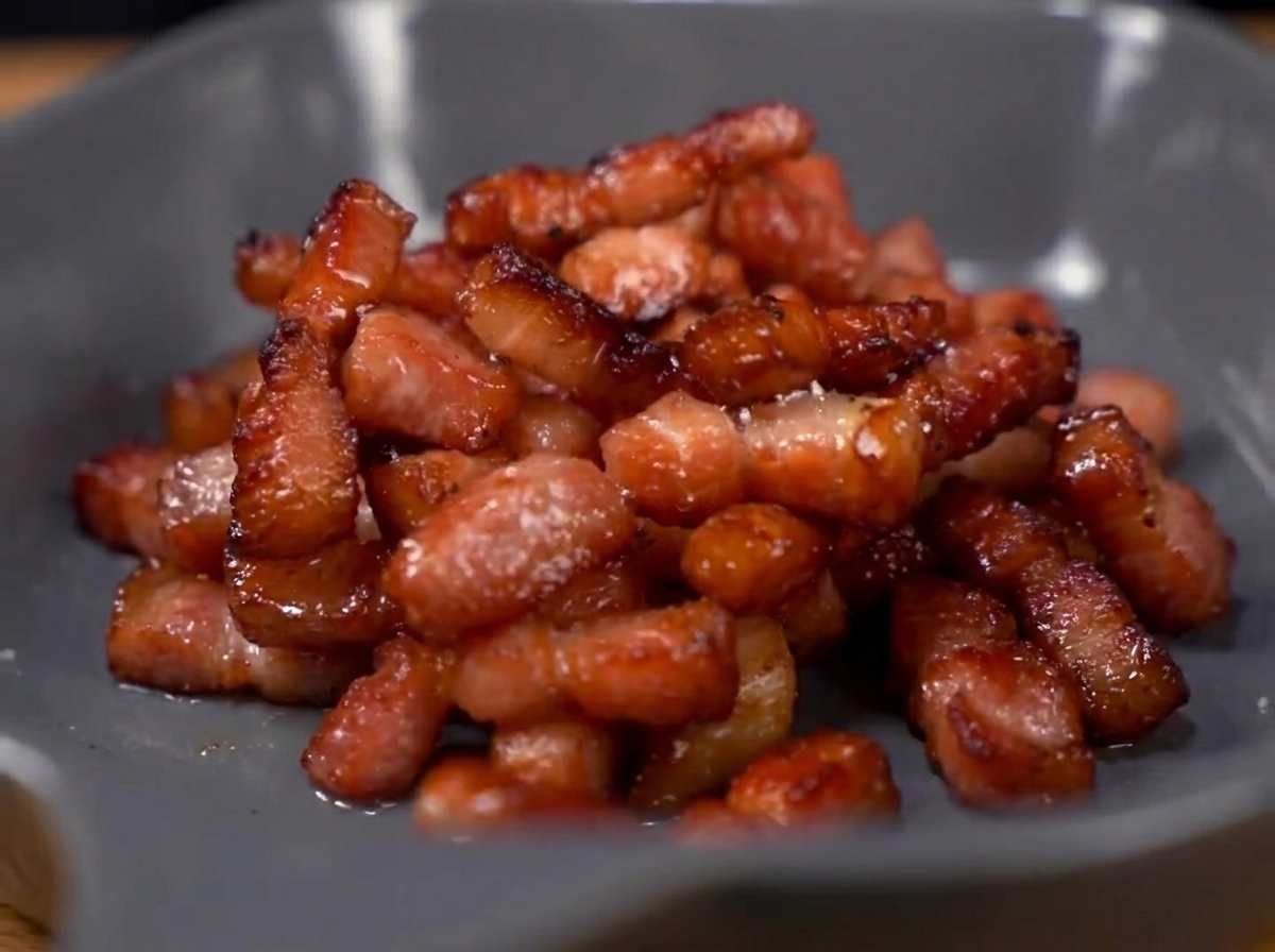 Asperges et petits pois en train de sauter dans une poêle avec les morceaux de bacon.
