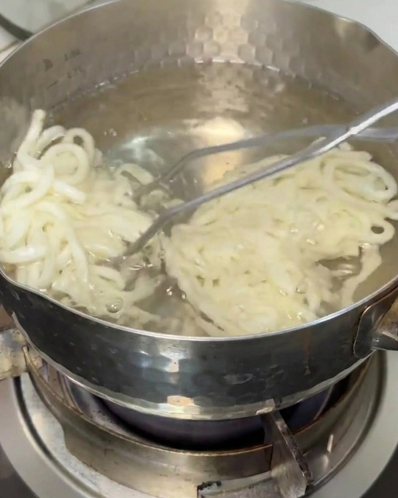 Nouilles udon extraites dune casserole deau bouillante avec une écumoire.