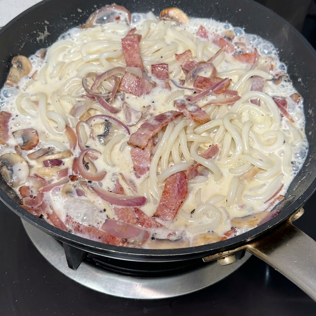 Pâte de truffe noire incorporée dans la poêle avec le bacon, les champignons et les oignons.