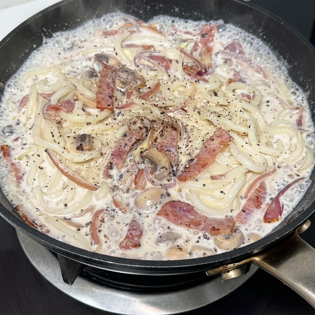 Poêle dudon crémeux au bacon et aux champignons assaisonnée de poivre noir.