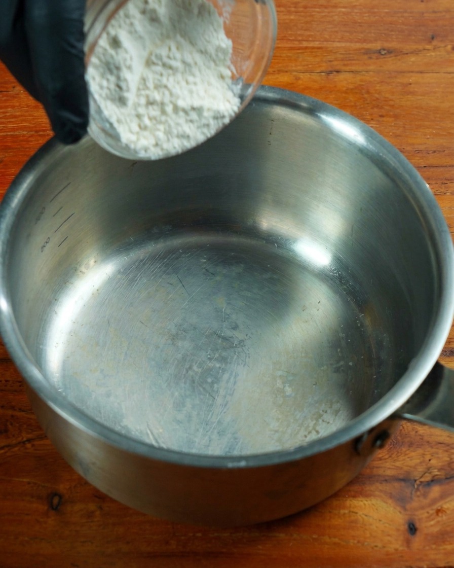 Farine pauvre en protéines remuée dans une casserole en inox à feu doux.