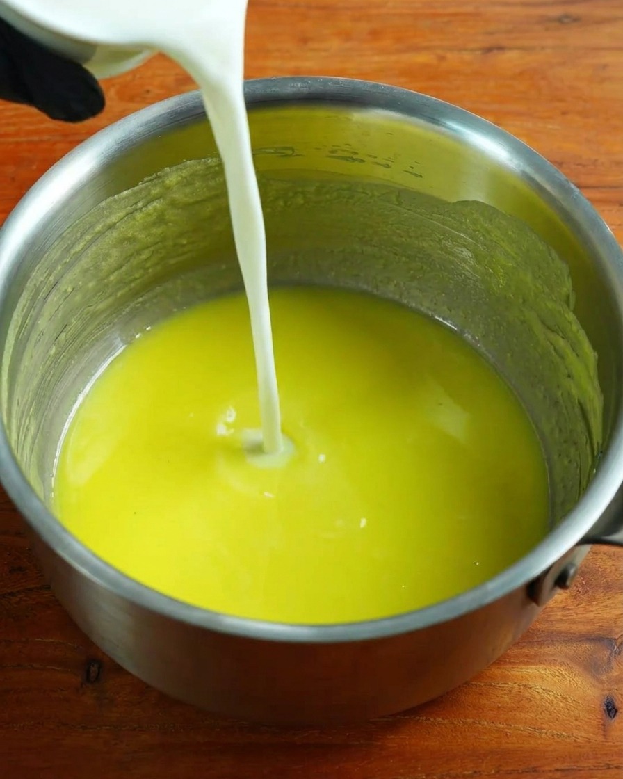 Lait chaud versé dans la base de roux tout en fouettant.