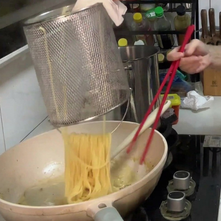 Spaghetti cuits transférés dans la poêle avec la sauce crémeuse aux champignons.