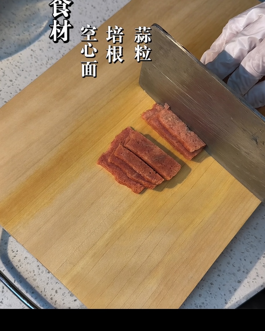 Tranches de bacon coupées en petits morceaux sur une planche en bois.