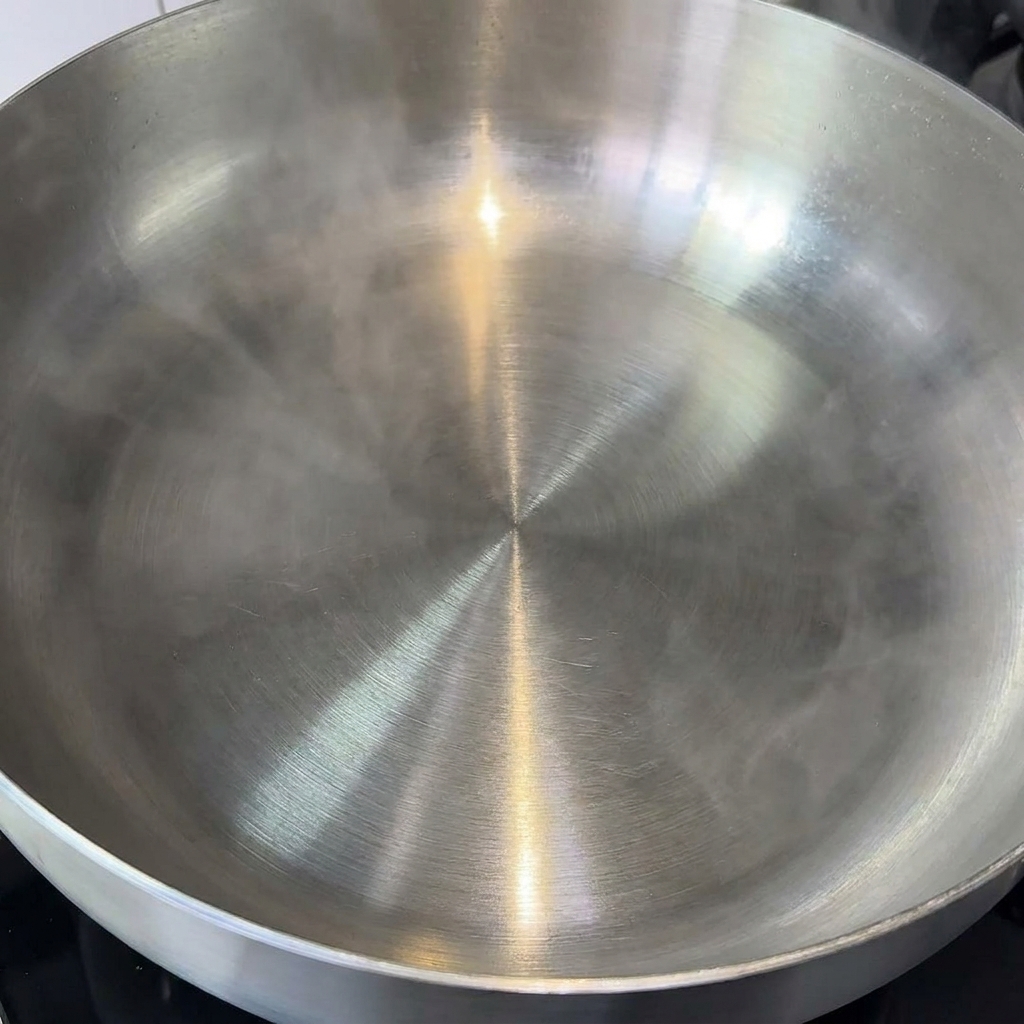 Un morceau de beurre fondant dans une grande poêle en inox propre.