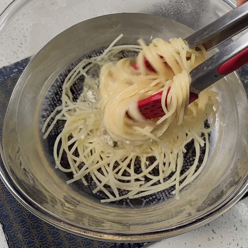 Spaghettis cuits égouttés dans une passoire en métal.