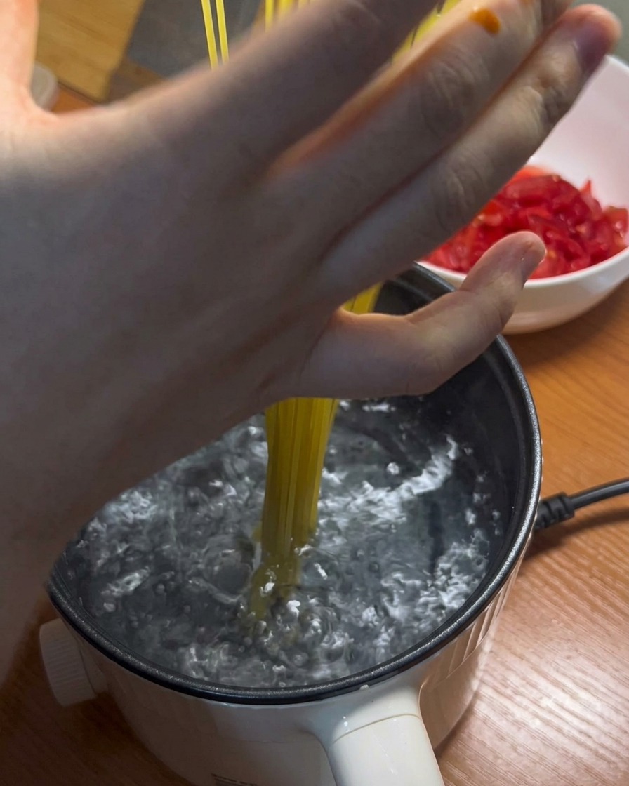 De longs spaghettis plongés dans une casserole deau bouillante.
