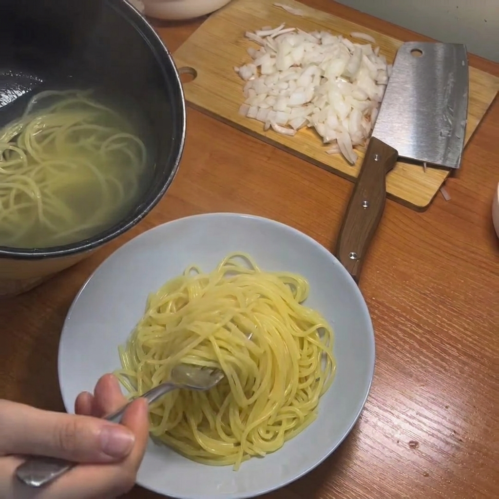 Des spaghettis cuits retirés de la casserole à laide de baguettes.