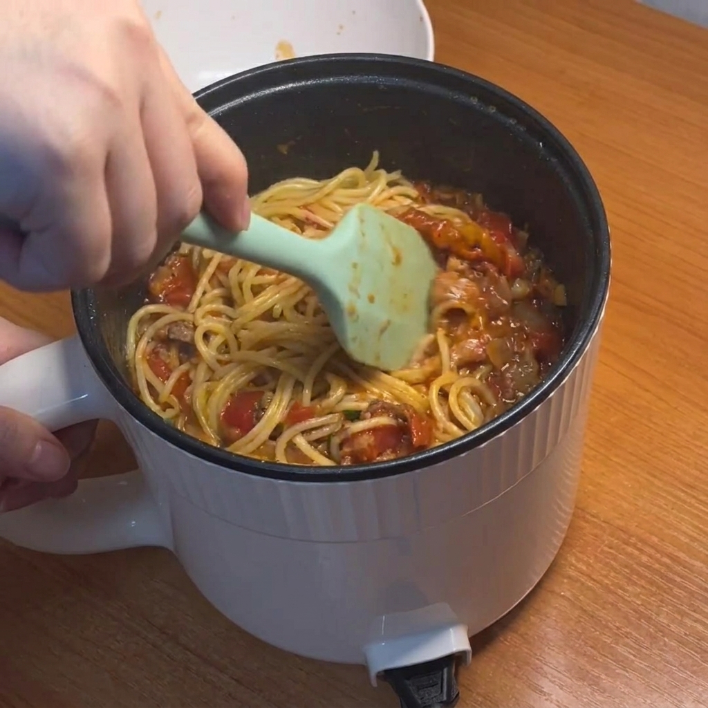 Des spaghettis remués vigoureusement et enrobés dune sauce tomate épaisse à la viande.