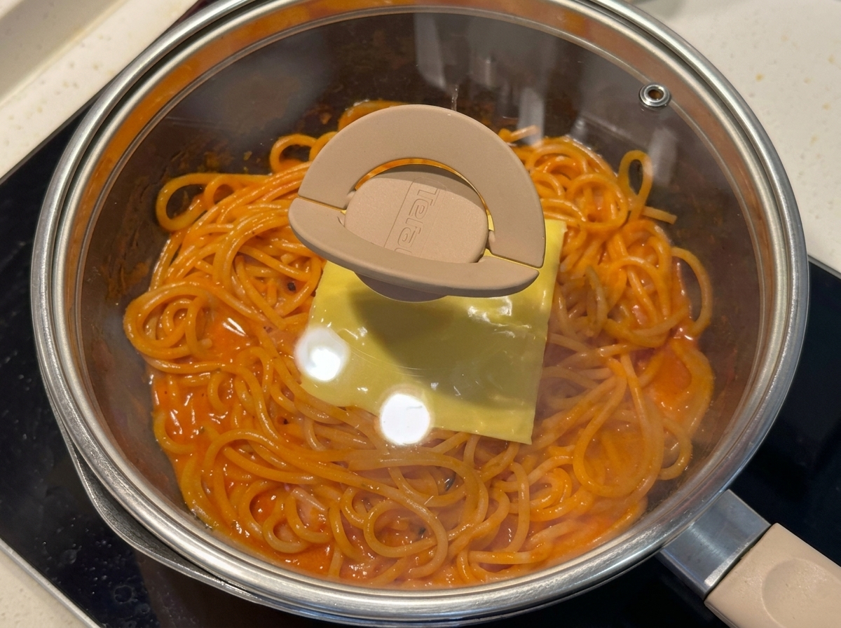 Poêle de spaghettis couverte dun couvercle en verre pour faire fondre le fromage.
