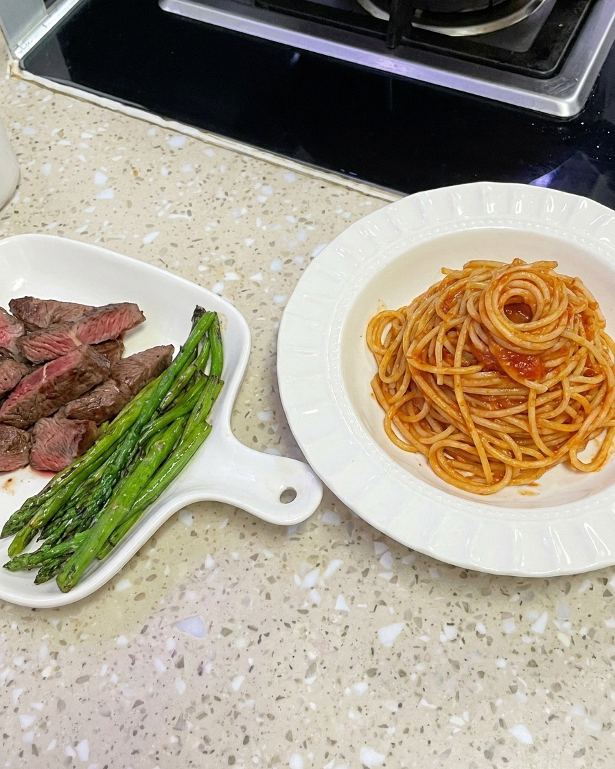 Spaghettis nappés de sauce soulevés avec une pince pour le dressage.