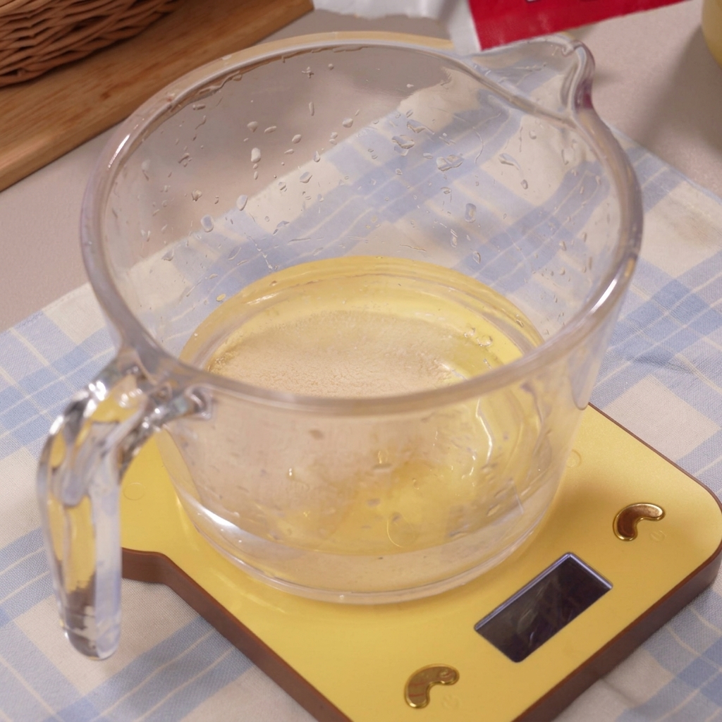La levure se dissolvant dans leau glacée claire à lintérieur de la tasse à mesurer.