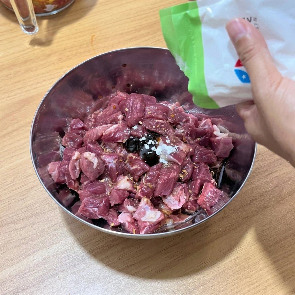 Les cubes de bœuf mélangés aux assaisonnements liquides et aux épices dans un bol.