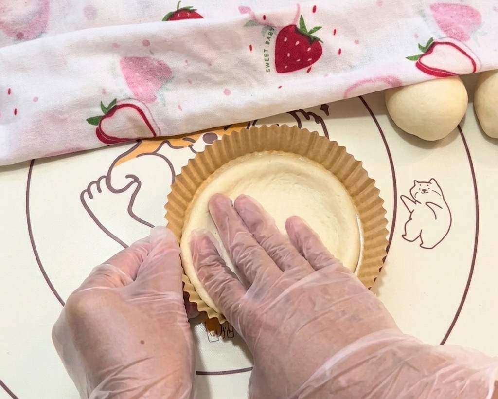 La pâte est étalée délicatement à la main dans des petits moules en papier ronds.